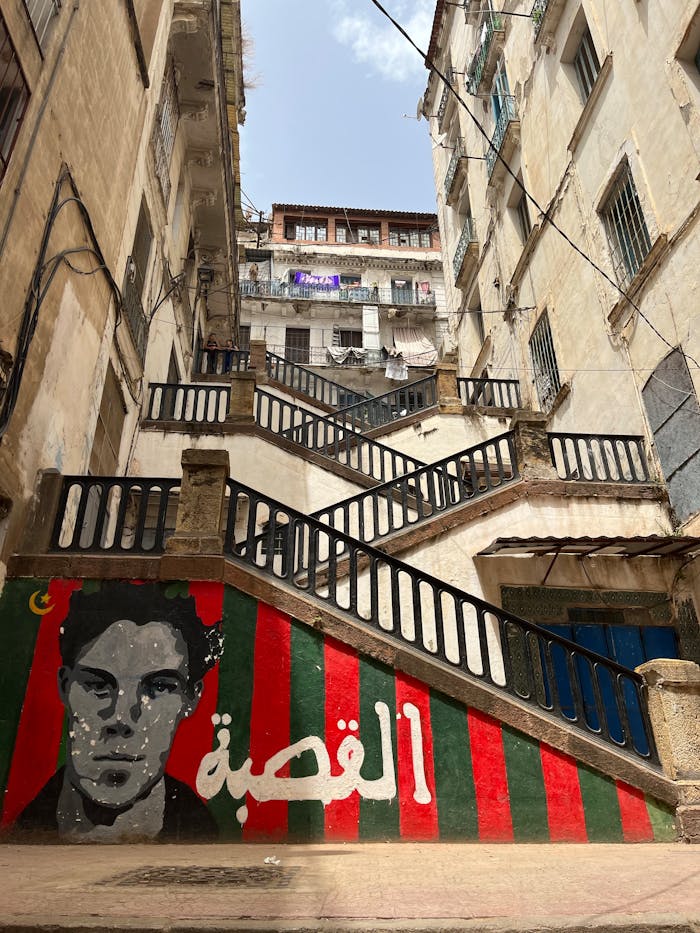 Low-angle view of historic architecture in Algiers with vivid graffiti art on a staircase.