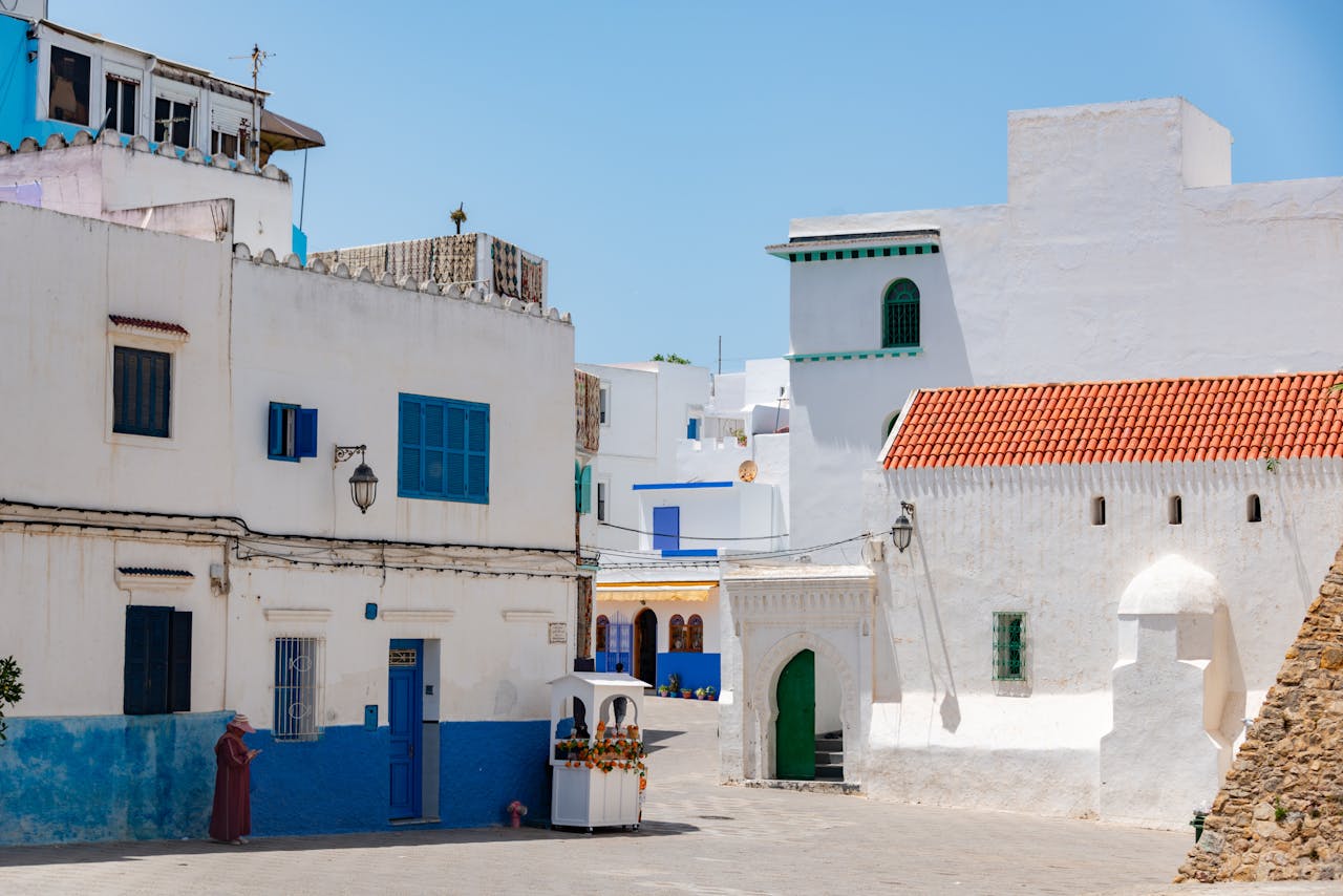 Charming alley in Asilah, Morocco, with vibrant blue and white architecture under a clear summer sky.