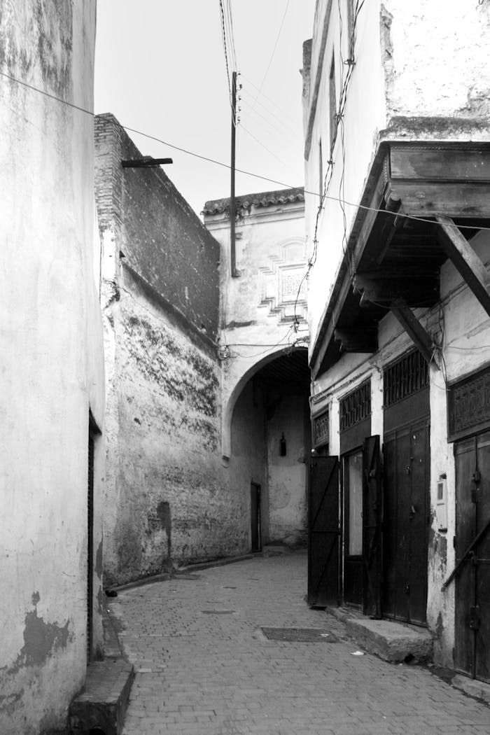 Black and white photo of old alleyway in Fes, showcasing traditional architecture.